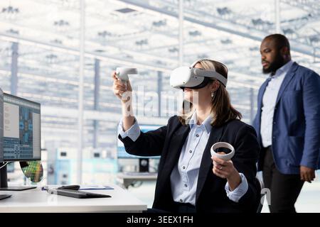 Testing microchip electronics prototypes, VR and multiethnic engineering team. Ensuring industrial hardware standards, virtual reality goggles and diverse coworkers in semiconductors RD laboratory Stock Photo