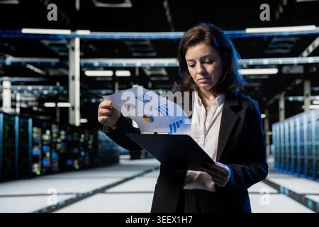 Server farm IT professional looking over maintenance diagnostic reports to optimize infrastructure performance. Data center admin crosschecking technical files to prevent unexpected system rigs bugs Stock Photo
