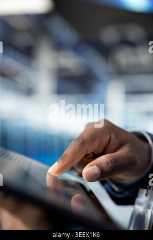 Close up of data center admin reviewing network configuration with tablet app, running predictive maintenance. Server farm worker scanning hardware logs with touchscreen device, tracking computer bugs Stock Photo