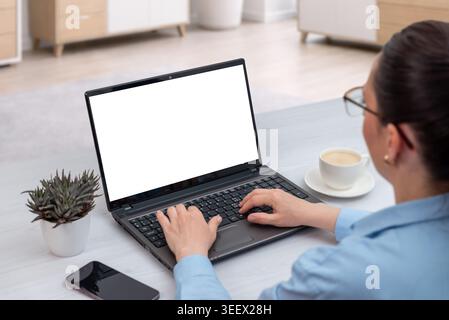 Female professional using laptop with isolated white screen in bright office interior, ideal mockup for software, education, banking or business prese Stock Photo
