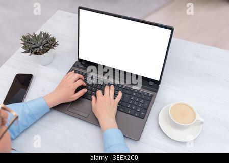 Top view office desk with woman using laptop mockup beside coffee and smartphone, ideal for remote work, business and modern technology concepts Stock Photo