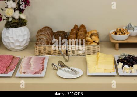Continental breakfast buffet with various cold cuts, cheese, grapes, and assorted bread items Stock Photo