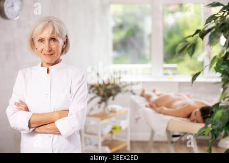 Elderly woman masseuse posing in spa salon Stock Photo