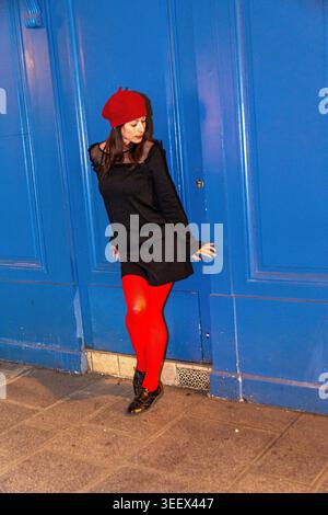 Woman wearing red beret and tights posing in urban setting Stock Photo