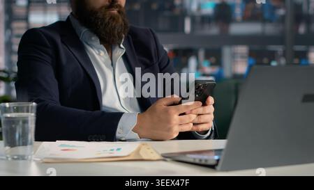 Browsing mobile apps as addictive habit and office work distraction, doomscrolling on social media and browsing through emails or texts. Adult male scrolling smartphone applications. Stock Photo