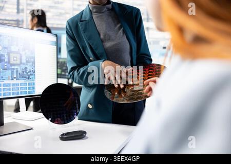 Doing quality inspection, silicon wafer close up and women in microchip factory RD lab. Examining intricate circuit patterns, semiconductor substrates and female engineers Stock Photo