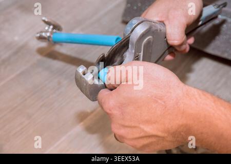 Plumber works on blue pipe fitting using wrench while fixing plumbing in home Stock Photo