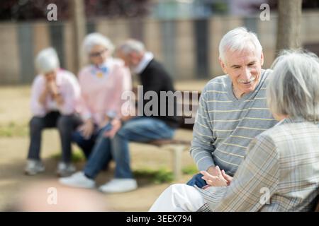 Elderly couple flirting while sitting on bench in courtyard Stock Photo