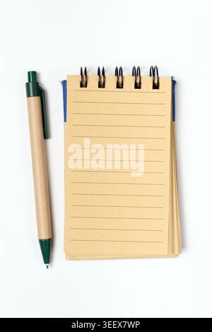 Top view of a spiral notepad with lined pages and an eco-style pen on a white background, representing organization, note-taking, planning, and productivity. Stock Photo
