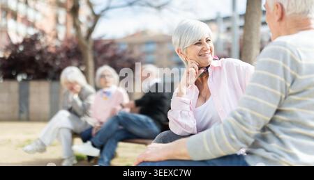 Elderly couple flirting while sitting on bench in courtyard Stock Photo