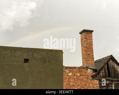A faint rainbow appearing over a rustic brick chimney and weathered outbuildings in a Serbian village after a spring storm. Stock Photo