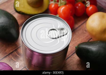 Can of food surrounded by fresh vegetables on a wooden table Stock Photo