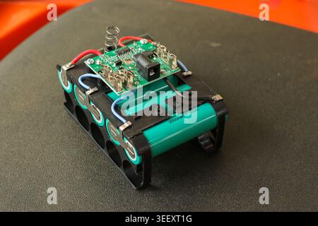 Close up view of custom built battery pack with circuit board and wires resting on dark surface, conveying sense of complex electronic engineering and Stock Photo
