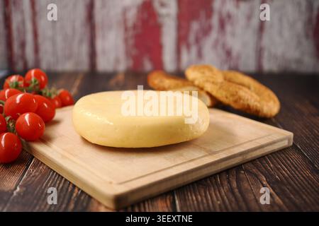 Cheese with cherry tomatoes and cookies on a wooden board Stock Photo
