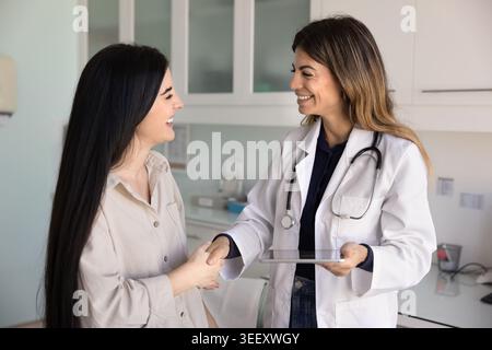 Smiling therapist shaking hands with young woman patient Stock Photo