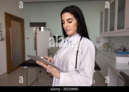 Focused Latina woman GP in uniform working on tablet Stock Photo