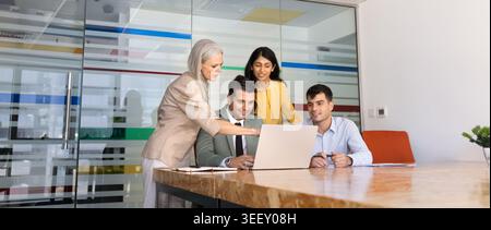 Diverse businesspeople discussing project on laptop in corporate office, banner Stock Photo