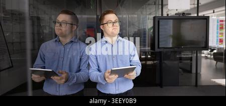 Professional man, corporate staff member with Down syndrome holding tablet Stock Photo