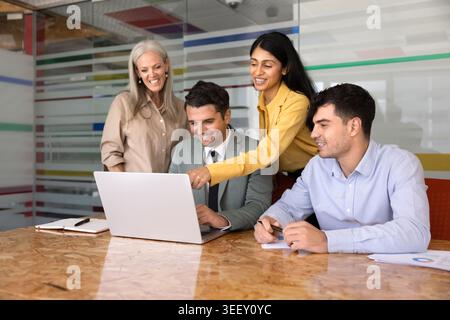 Smiling multiethnic businesspeople discussing project data on laptop Stock Photo