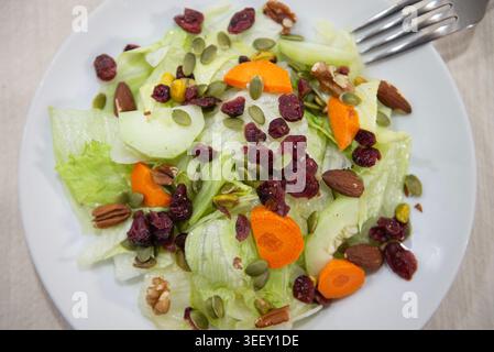 Salad with lettuce, cucumber, carrot, grains and seeds, on a table, top view with a fork in the background, food and lifestyle Stock Photo