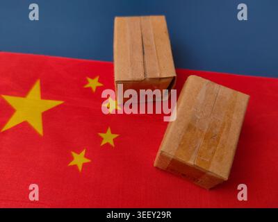 Two brown cardboard shipping boxes placed on top of a Chinese flag represent international trade and logistics. Stock Photo