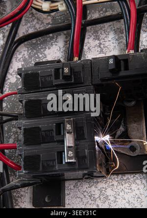 Residential electrical load center, with a fault in the thermomagnetic circuit breaker causing a spark in one of its phases due to a bad connection Stock Photo