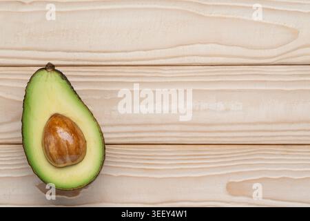 Avocado half on light wooden background with copy space Stock Photo