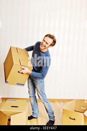 Smiling young man carrying many cardboard boxes Stock Photo