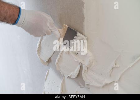 Applying joint compound with a putty knife to smooth imperfections on drywall surface. Clean and bright workspace provides optimal conditions for finishing work. Stock Photo
