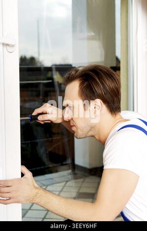 Young handyman repair window with screwdriver Stock Photo