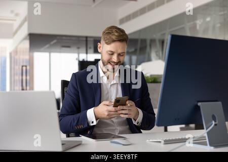 Smiling professional man, office employee using smartphone Stock Photo