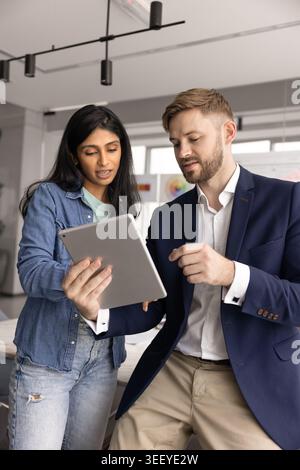 Two multiethnic male, female colleagues using tablet Stock Photo