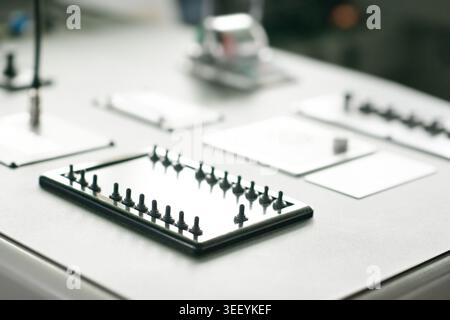 Industrial control panel with rows of toggle switches, reflective metal plates, grey console surface, and blurred electrical controls in the backgroun Stock Photo