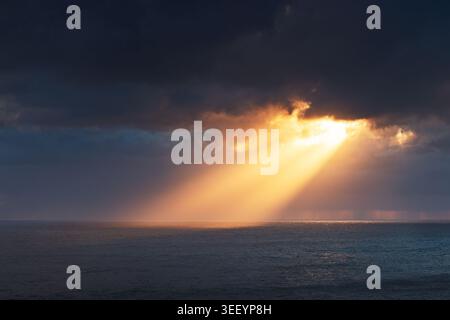 Dramatic Sun Rays over Sea Surface during Stormy Sunset Stock Photo