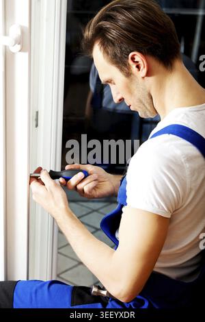 Young handyman repair window with screwdriver Stock Photo