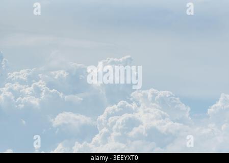 Soft white clouds floating across pale blue sky with peaceful atmosphere and natural daylight background for weather and nature themes Stock Photo