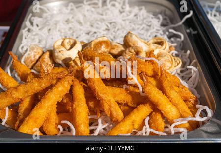 Golden crispy shrimp and fried dumplings served on a bed of crunchy noodles. Perfect for a savory snack or appetizer Stock Photo