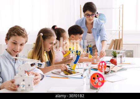 Children Engaged in a Robotics Class With a Teacher Guiding Their Projects in a Bright Classroom Stock Photo