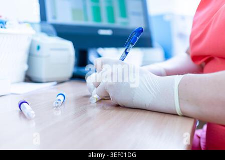 Hantavirus concept. Doctors hand writes on a blood samples in the laboratory. Close-up. Stock Photo
