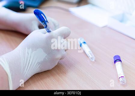 Hantavirus concept. Doctors hand writes on a blood samples in the laboratory. Close-up. Stock Photo
