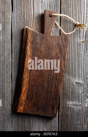 Small knife with wooden handle lying on an old cutting board on rusty aged table Stock Photo
