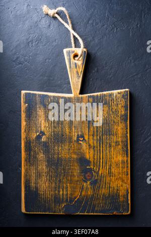 Small knife with wooden handle lying on an old cutting board on rusty aged table Stock Photo
