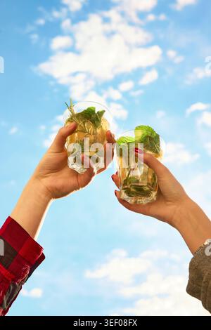 Friends clinking mint cocktails under bright summer sky Stock Photo