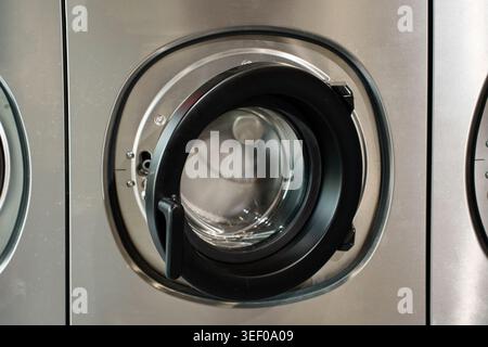 Close up of an open commercial washing machine door in a laundromat Stock Photo