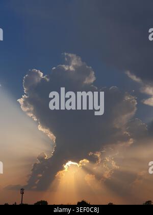 Phone photo of dramatic clouds with sun rays bursting from behind. Atmospheric sky scene showing contrast, light beams, and natural landscape mood. Stock Photo