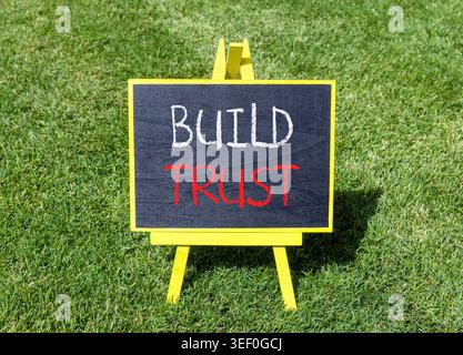 Build trust symbol. Concept words Build trust on beautiful black blackboard. Beautiful green grass lawn background. Business and build trust concept, Stock Photo