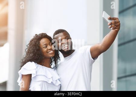 Couple Enjoys a Joyful Moment Taking a Selfie on a Sunny Day Outdoors Stock Photo