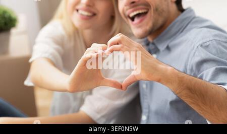 Smiling Husband And Wife Gesturing Heart Shape With Hands, Cropped Stock Photo