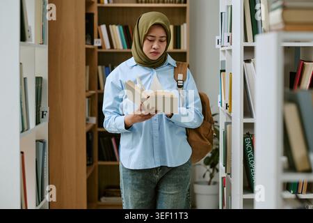 Adult Muslim Woman Reading Book in Library for Education Access Stock Photo