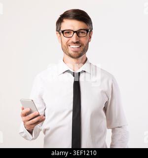 Professional Man Stands With Phone Showing a Friendly Expression in a Studio Setting Stock Photo